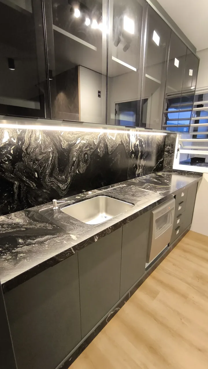 Bancada e painel de cozinha em pedra escura com veios brancos