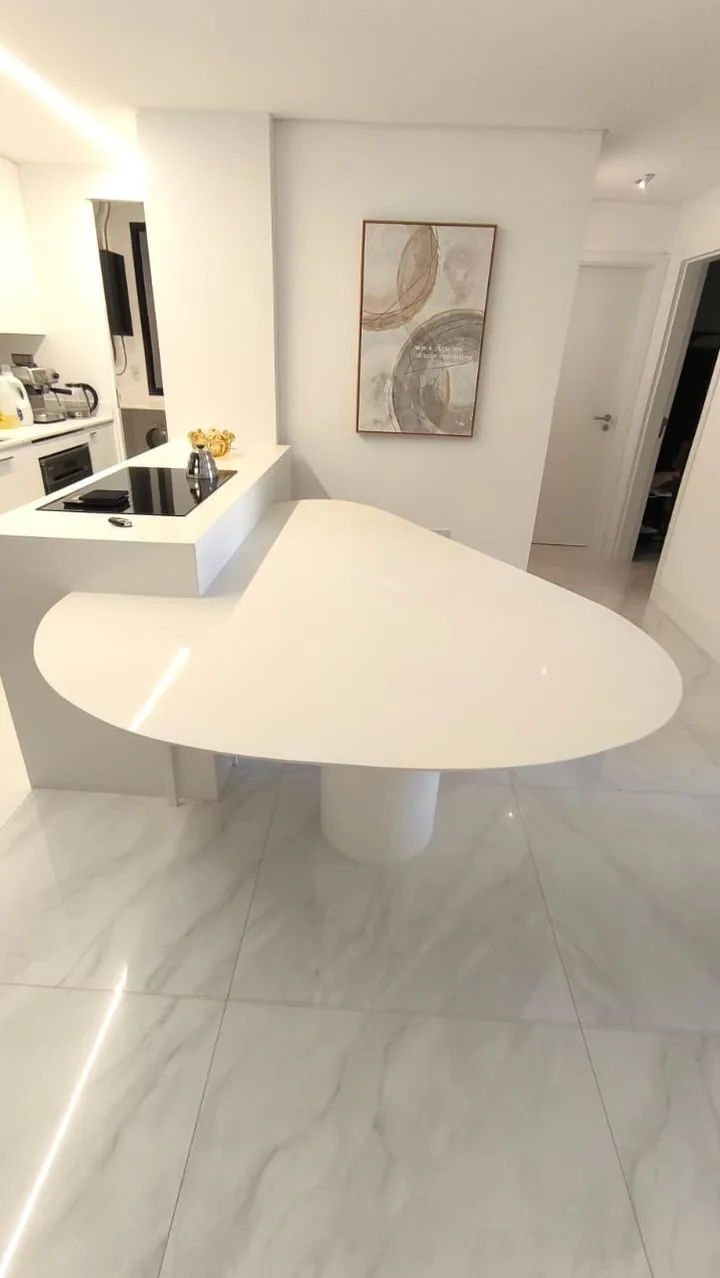 Ilha branca com cooktop e mesa integrada em formato orgânico